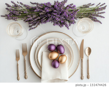 Luxury Happy Easter. Elegant top view, layout, minimalist style, Easter decorated table with golden eggs and lavender bouquet arranged on napkin with matching cutlery and glassware. 131474426