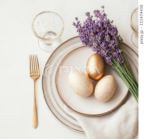 Luxury Happy Easter. Elegant top view, layout, minimalist style, Easter decorated table with golden eggs and lavender bouquet arranged on napkin with matching cutlery and glassware. Luxury Happy Easter. Elegant top view, layout, minimalist style, Easter decorated table with golden eggs and lavender bouquet arranged on napkin with matching cutlery and glassware. 131474430