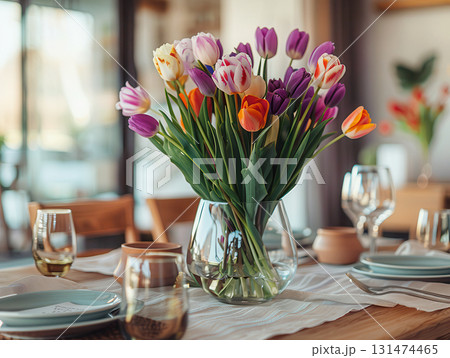 Fresh spring bouquet of pastel tulips in a clear glass vase, placed in a cozy, sunlit kitchen with mint green cabinets and a soft homely feel. 131474465