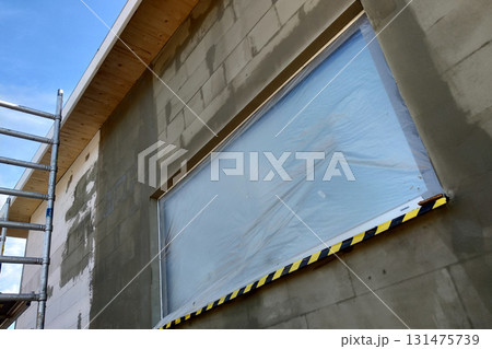 Window of a house under construction covered with protective plastic film. 131475739