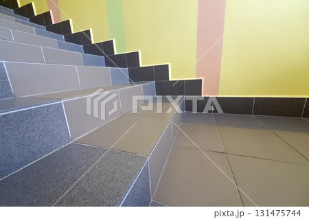 Wide staicase covered with ceramic tiles indoors in a house interior. 131475744