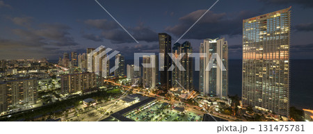 View from above of brightly illuminated high skyscraper buildings in downtown district of Sunny Isles Beach city in Florida, USA. American tourist urban district at night 131475781