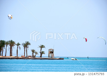 Tropical sea pier with palms and recreational zone, tourists windsurfing and kite surfing. Summer exotic vacations 131475793