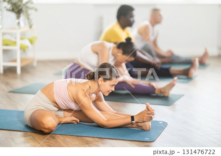 Young woman doing yoga in group in studio 131476722