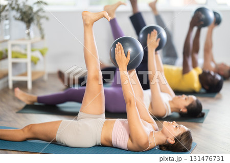 Young woman doing pilates with soft ball in group 131476731