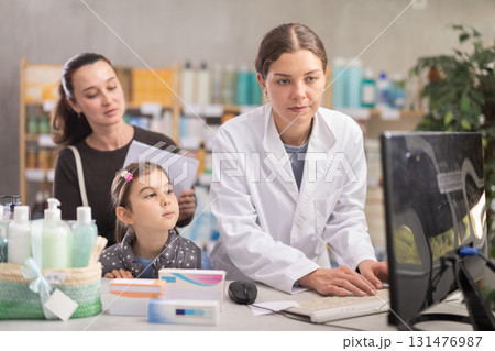 Pharmacist recommending medicines to mom with child at drugstore counter 131476987