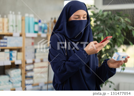 Young Muslim woman customer scanning QR-code on ointment box 131477054