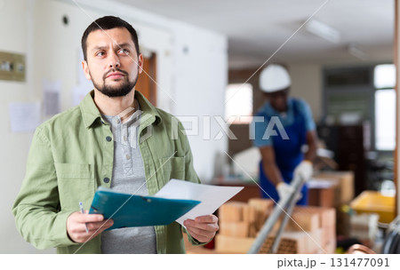 Portrait of construction manager with documents standing in building site Portrait of construction manager with documents standing in building site 131477091