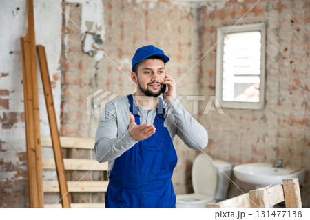 Builder talking on phone at construction site Builder talking on phone at construction site 131477138