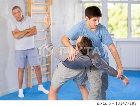 Two athlete men of different age in sportswear practicing self-defense sparring in hall 131477195