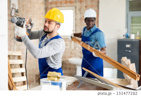 Two builders working on indoor construction site 131477282