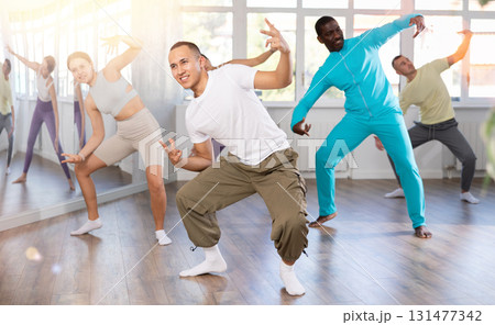 Young happy guy and international dancers preparing their modern dance at dance studio 131477342