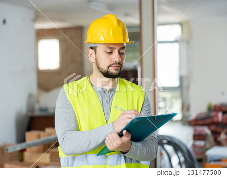 Qualified builder writes notes on a tablet Qualified builder writes notes on a tablet 131477500
