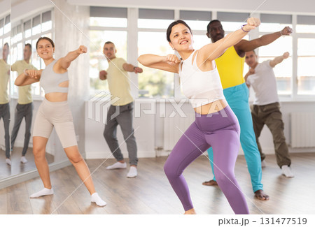 Young Asian woman practicing vigorous zumba with group 131477519