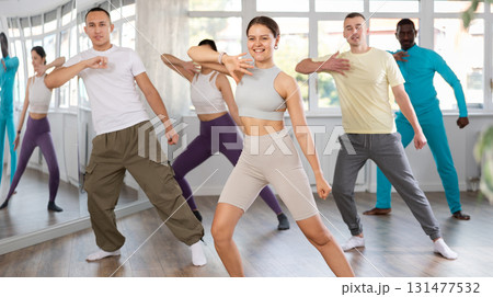 Happy girl and group of multinational young people practicing new modern dance techniques at dance school Happy girl and group of multinational young people practicing new modern dance techniques at dance school 131477532