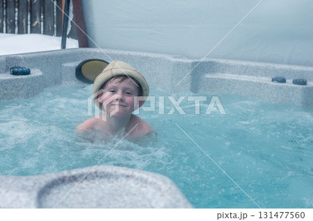 Cheerful happy family with children enjoys hot bath in jacuzzi whirlpool on cold winter day. Carefree relaxation in hot tub outdoors of nature. Meeting and chatting with relatives. 131477560