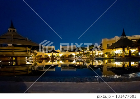 Calm serene view of pool, hotel, palm trees at night with bright lanterns. Vacation concept. High quality photo 131477603