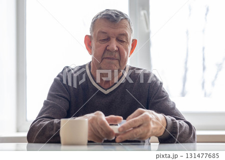 Portrait of elderly man. Senior takes pills sitting at table. High quality photo Portrait of elderly man. Senior takes pills sitting at table. High quality photo 131477685