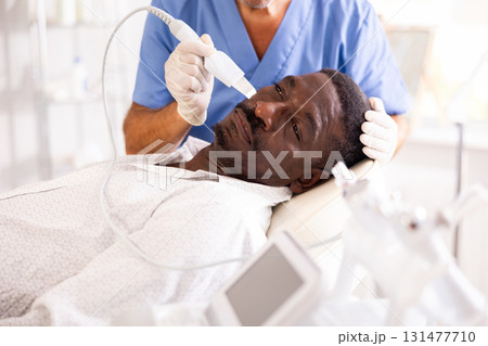 Doctor uses scriber beauty machine nozzle for gentle skin peeling for African-American man client Doctor uses scriber beauty machine nozzle for gentle skin peeling for African-American man client 131477710