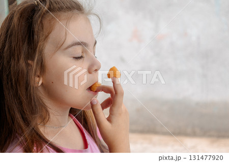 Young girl is holding yellow raspberries on her fingers and tasting. High quality photo 131477920