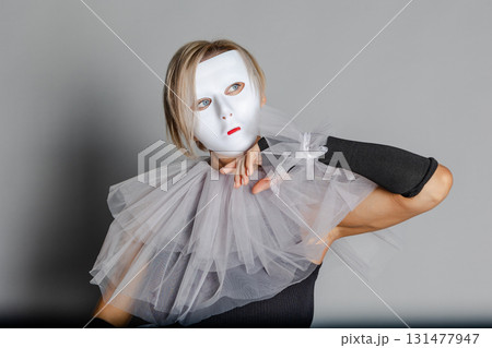 Face behind mask. Woman in white theater mask and harlequin collar on gray background. Fancy dress, masquerade clothes  131477947