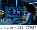 Female data scientist working late on facial recognition software in modern tech office with futuristic digital displays 131477987