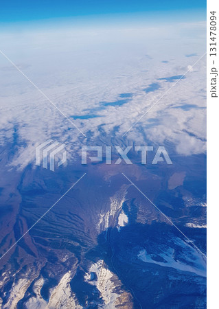 View from window of plane to blue sky and snowy mountain peaks in white clouds. High quality photo View from window of plane to blue sky and snowy mountain peaks in white clouds. High quality photo 131478094