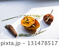 Dried pumpkin - container with a lid and a dried mandarin with a leaf, horsetail, and a spruce cone on a white background. Still life. 131478517