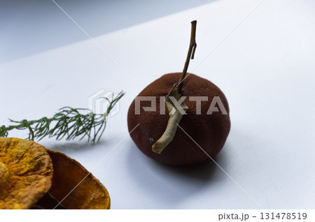 Dried pumpkin - container with a lid and a dried mandarin with a leaf, horsetail, and a spruce cone on a white background. Still life. 131478519