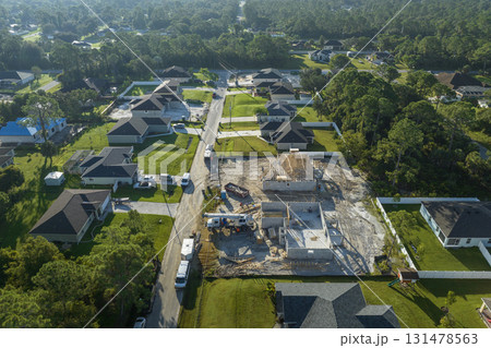 Professional builders working on roof construction of unfinished suburban home with wooden frame structure in Florida rural area. Concept of housing development in America Professional builders working on roof construction of unfinished suburban home with wooden frame structure in Florida rural area. Concept of housing development in America 131478563