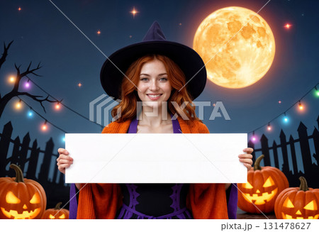 young woman in witch costume holding blank banner against background of pumpkins and full moon 131478627
