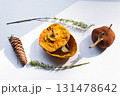 Dried pumpkin - container with a lid and a dried mandarin with a leaf, horsetail, and a spruce cone on a white background. Still life. 131478642