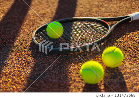 Tennis ball with rocket near grid at outdoor summer sunny court closeup 131478669