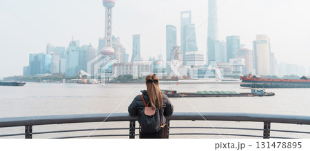 woman traveler visiting in Shanghai, China. Female Tourist with backpack sightseeing Shanghai view of Lujiazui in The Bund of Shanghai. landmark and popular for tourism attractions. Vacation concept 131478895