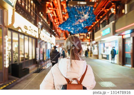 woman traveler visiting in Shanghai, China. Happy Female Tourist sightseeing and shopping in Yuyuan Old Street market at night. landmark and popular for tourism attractions. Travel and Vacation 131478916