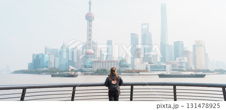 woman traveler visiting in Shanghai, China. Female Tourist with backpack sightseeing Shanghai view of Lujiazui in The Bund of Shanghai. landmark and popular for tourism attractions. Vacation concept 131478925