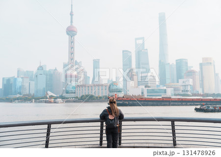 woman traveler visiting in Shanghai, China. Female Tourist with backpack sightseeing Shanghai view of Lujiazui in The Bund of Shanghai. landmark and popular for tourism attractions. Vacation concept 131478926
