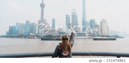 woman traveler visiting in Shanghai, China. Female Tourist with backpack sightseeing Shanghai view of Lujiazui in The Bund of Shanghai. landmark and popular for tourism attractions. Vacation concept 131478961