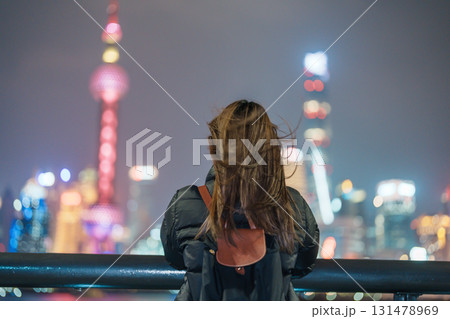 woman traveler visiting in Shanghai, China. Female Tourist with backpack sightseeing Shanghai view of Lujiazui in The Bund of Shanghai at night. landmark and popular for tourism attractions 131478969