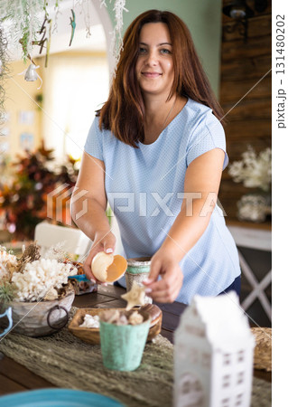 Domestic woman putting blue ceramic dishes on wickered holder serving kitchen desk at home 131480202