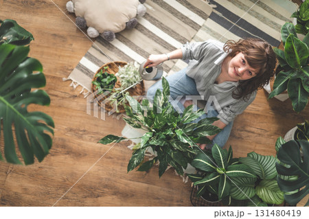 A young woman enjoys caring for flowers. Watering indoor plants and admiring them. A young woman enjoys caring for flowers. Watering indoor plants and admiring them. 131480419