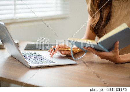 Female businessman working with holding a pen and using a calculator to calculate the numbers of static at home office. Female businessman working with holding a pen and using a calculator to calculate the numbers of static at home office. 131483176