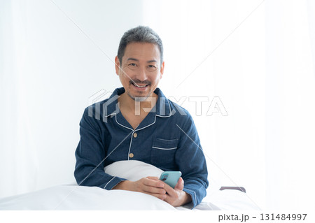 寝室でスマホを見るミドルの男性 131484997