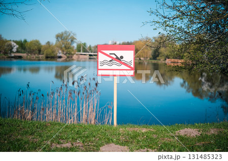 Swimming prohibited sign on the shore of a body of water Swimming prohibited sign on the shore of a body of water 131485323