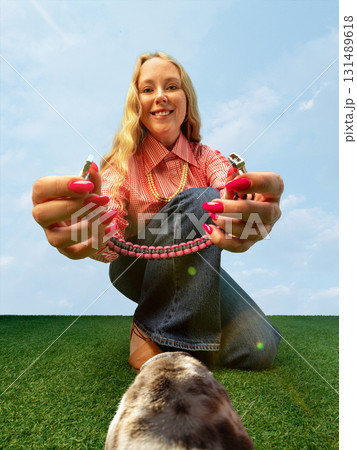 Smiling woman showing pink dog collar from animal playful ground-level view 131489618