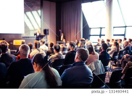 Speaker giving a talk in conference hall at business event. Rear view of unrecognizable people in audience at the conference hall. Business and entrepreneurship concept Speaker giving a talk in conference hall at business event. Rear view of unrecognizable people in audience at the conference hall. Business and entrepreneurship concept 131493441