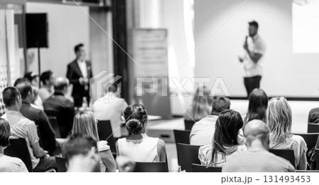 Business and entrepreneurship symposium. Speaker giving a talk at business meeting. Audience in conference hall. Rear view of unrecognized participant in audience. Business and entrepreneurship symposium. Speaker giving a talk at business meeting. Audience in conference hall. Rear view of unrecognized participant in audience. 131493453
