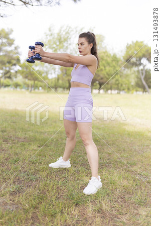 Active young woman exercising with dumbbells in park Active young woman exercising with dumbbells in park 131493878