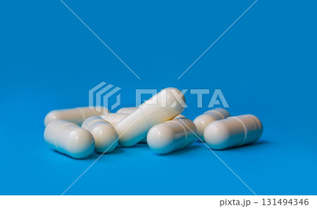Pills spilled out of white bottle on blue background. Mock up for special offers as advertising or other ideas. Medical, pharmacy and healthcare concept. Copy space. Empty place for text or logo. Pills spilled out of white bottle on blue background. Mock up for special offers as advertising or other ideas. Medical, pharmacy and healthcare concept. Copy space. Empty place for text or logo. 131494346