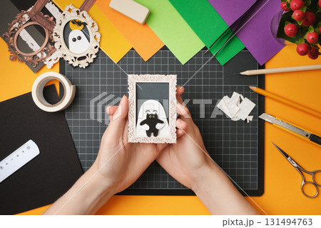 The process of creating a Halloween craft. A finished craft in the form of a portrait of a ghost with a black cat. The process of creating a Halloween craft. A finished craft in the form of a portrait of a ghost with a black cat. 131494763